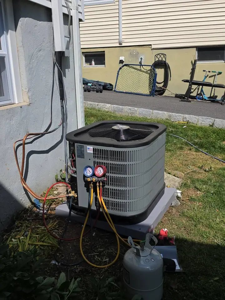 Outdoor A/C condenser being charged with gauges attached